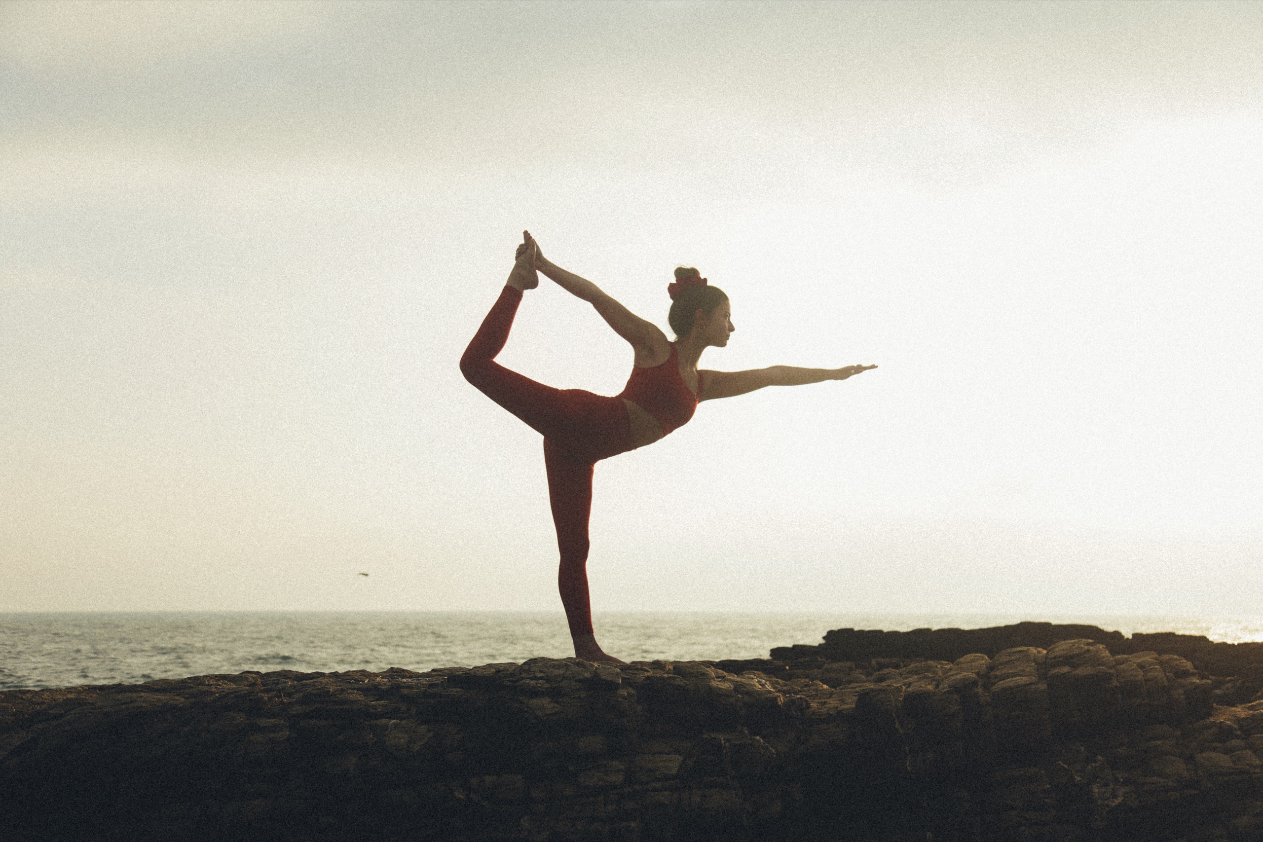 Daniela Roberts en postura de bailarín sobre las rocas frente al mar